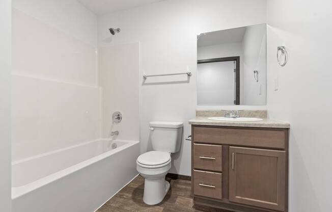 A white toilet sits in a bathroom next to a sink and a bathtub.