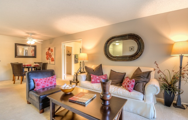 A living room with a black leather chair and a white couch with pink pillows.