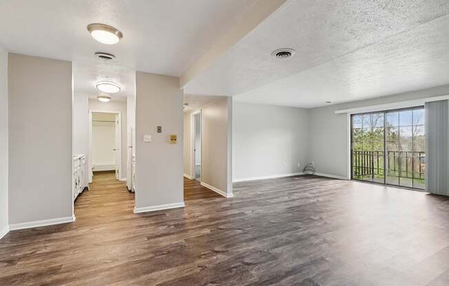 A spacious room with wooden flooring and white walls.