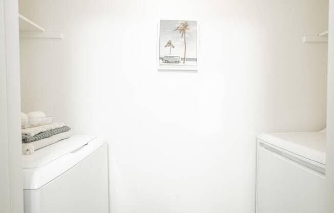 a small bathroom with a washer and dryer and a picture of a beach