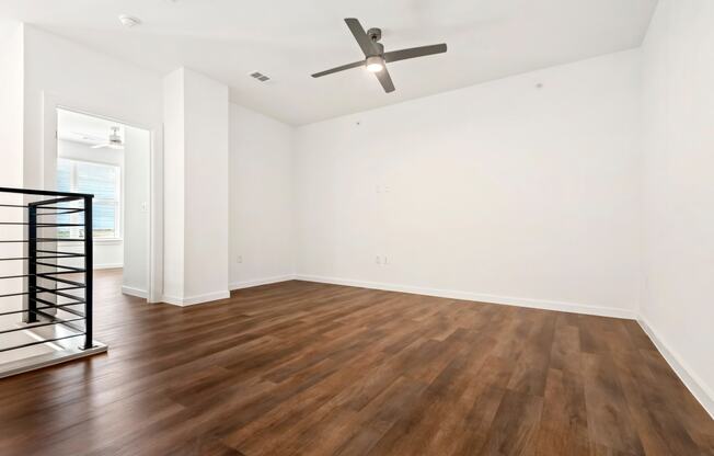 an empty living room with hardwood floors and a ceiling fan