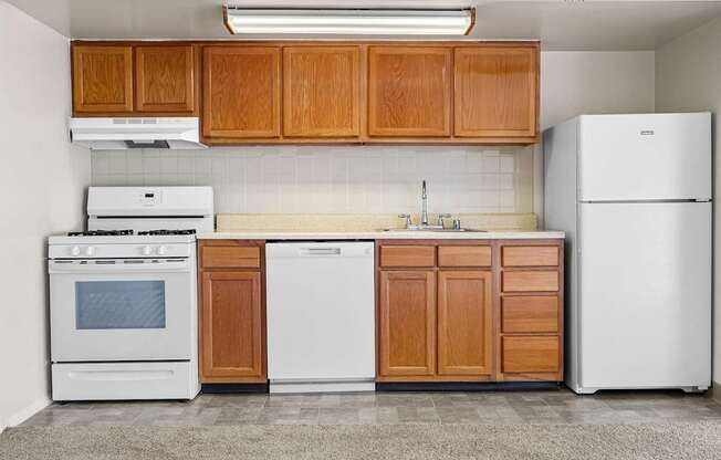 A kitchen with white appliances and wooden cabinets.