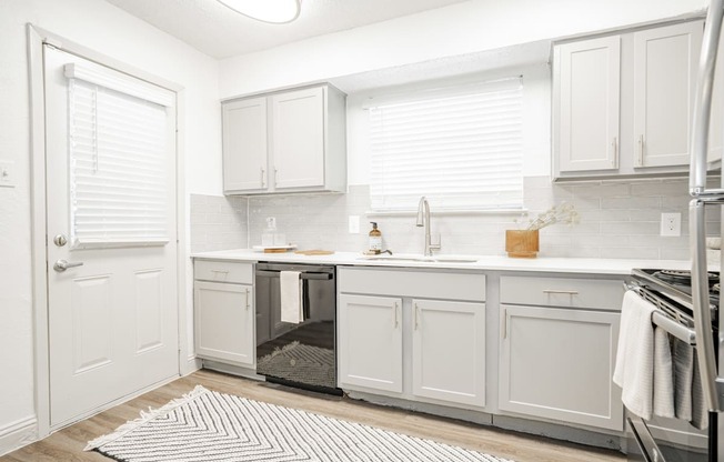 a white kitchen with white cabinets and a stainless steel refrigerator