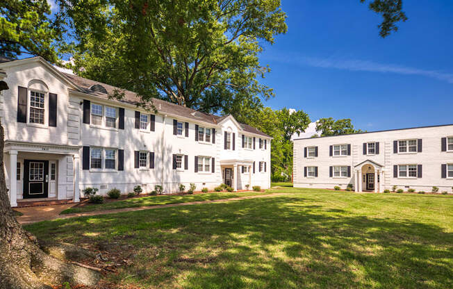 A white building with a black door and windows is surrounded by trees.