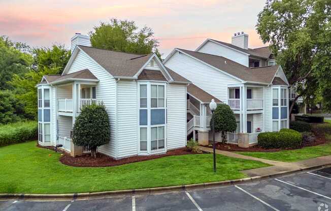 A white house with a brown roof and a green lawn.
