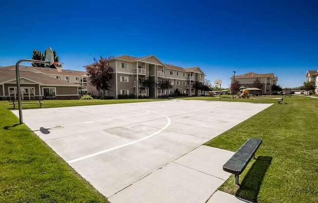 A basketball court in front of apartment buildings on a sunny day.