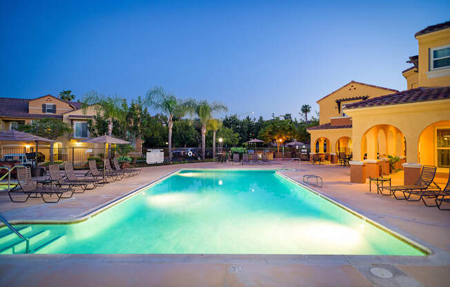 A large swimming pool surrounded by lounge chairs and palm trees.