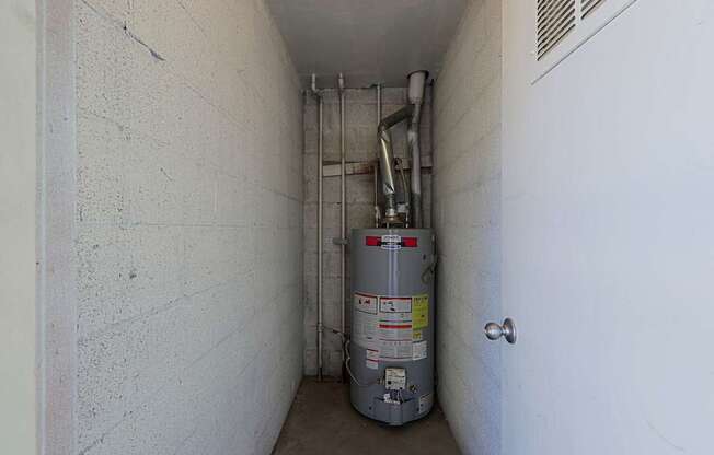 A silver metal container with red and yellow labels is in a white hallway.