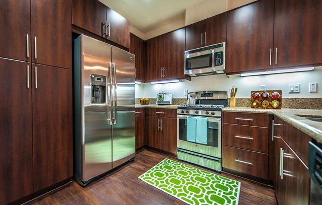 a kitchen with stainless steel appliances and wooden cabinets at The Vines at Riverpark, LLC, Oxnard California