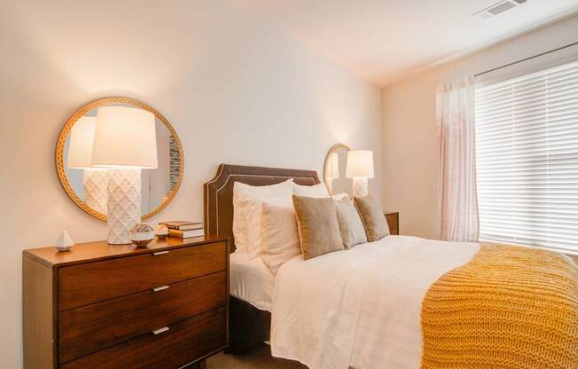 A bedroom with a bed, nightstand, and lamp.