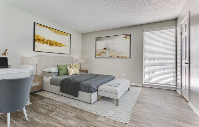 a bedroom with a bed and a desk and a window