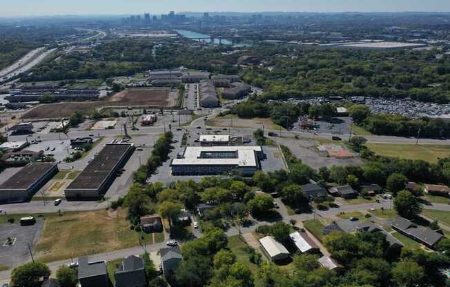 An aerial view of a large industrial area with buildings, roads, and a body of water in the distance.