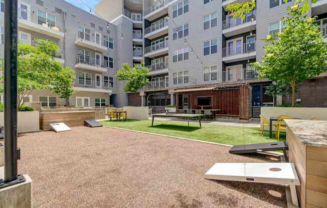 A courtyard with a picnic table and chairs is surrounded by apartment buildings.
