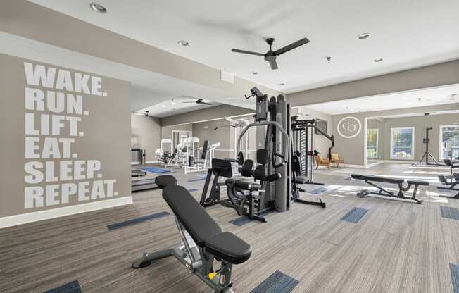 a gym with weights and a ceiling fan and a quote on the wall