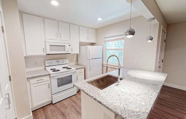 A kitchen with a granite counter top and white cabinets.