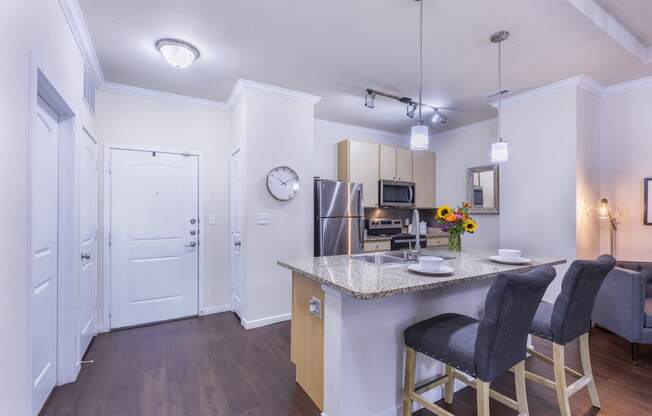 a kitchen and living room with a marble counter top and bar stools