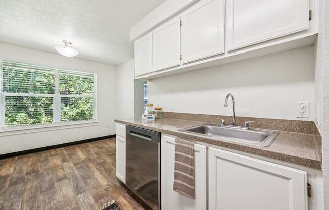 A kitchen with a stainless steel sink and a window with blinds.