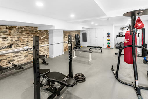 a gym with weights and other equipment and a stone wall