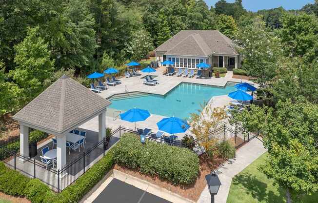 A pool surrounded by trees and a gazebo.