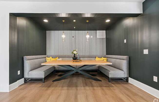 A modern dining area with a grey sofa and a wooden table.