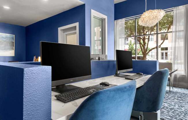A blue chair is in front of a desk with a computer monitor and keyboard.