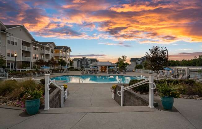 a swimming pool at sunset with apartments in the background