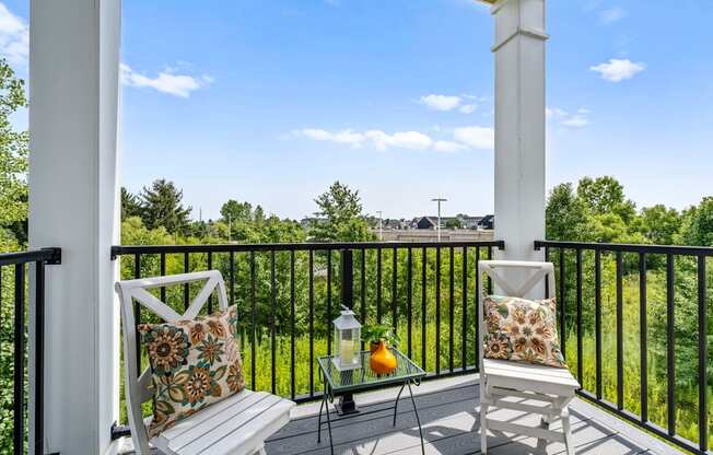 A white chair with a floral pillow is on a porch.