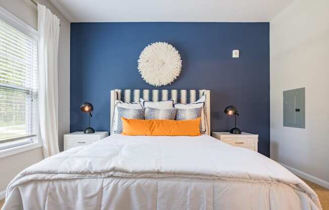 a bedroom with blue walls and a white bed with orange pillows