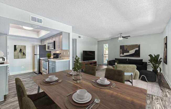 A dining table set with plates and cutlery is in the foreground of a modern kitchen and living room.