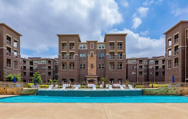 A large swimming pool in front of apartment buildings.