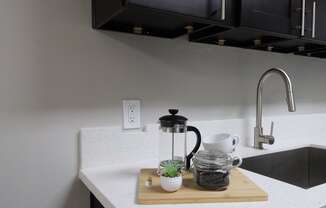 a kitchen sink with a coffee maker on a cutting board