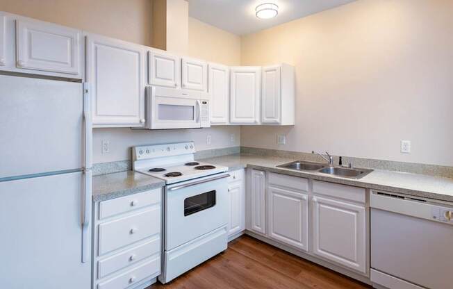 A white kitchen with a refrigerator, stove, oven, microwave, and cabinets.