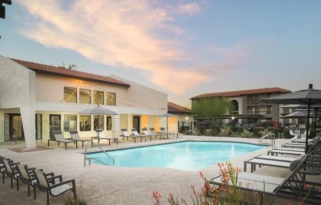 a swimming pool at a resort with chairs and umbrellas