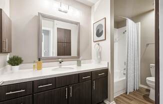 A bathroom with a white counter top and brown cabinets.