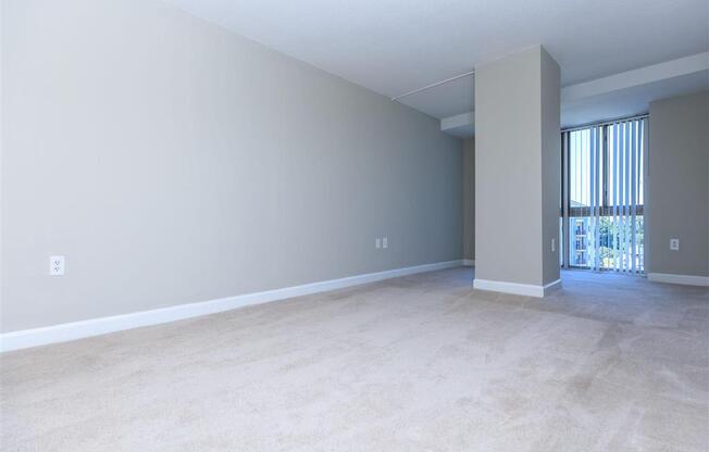 an empty living room with a sliding glass door and a balcony