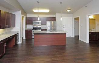 A kitchen with dark wood floors and white walls.