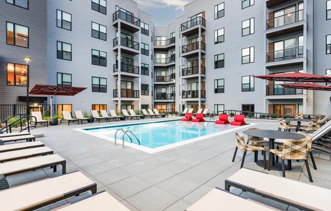 A vibrant pool courtyard with shaded seating and lounge chairs at Modera LoSo.