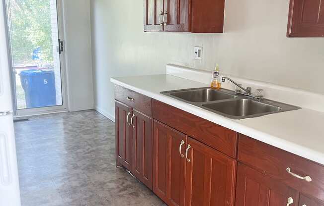 A kitchen with wooden cabinets and a double sink