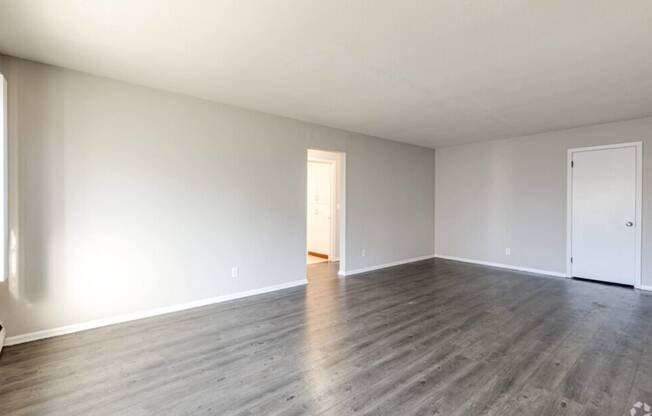 an empty living room with white walls and wood floors