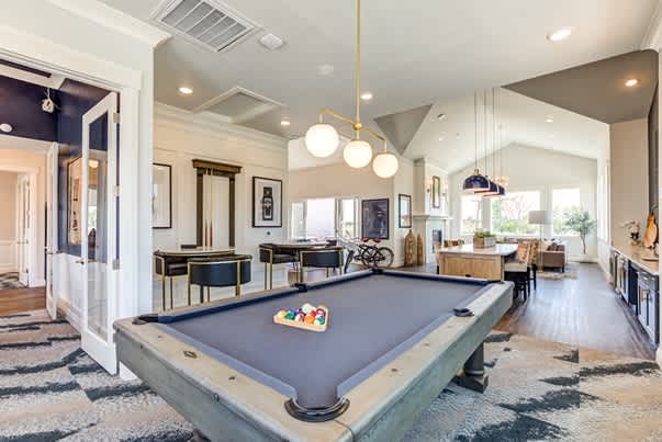 A pool table is in the middle of a room with a striped rug. at Connect at First Creek Apartments, Denver, Colorado