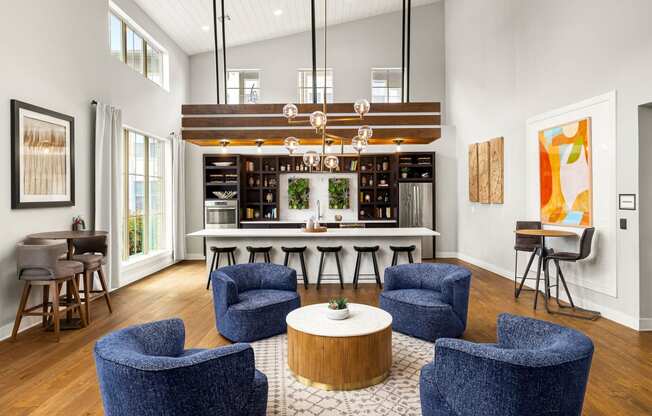 a living room with blue chairs and a kitchen with a bar