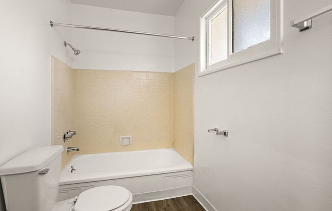 A white toilet sits next to a bathtub in a bathroom.