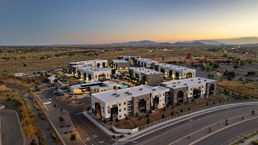 A modern building complex is situated on a road with a clear sky above.