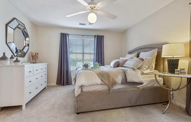staged bedroom with carpeted flooring, ceiling fan, and window