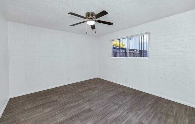 A room with a ceiling fan and a window with bars at The Phoenix Apartments on 6th Avenue, Phoenix, Arizona