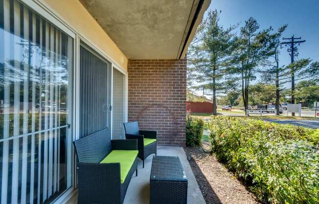 A patio with a bench and a table with a green cushion.