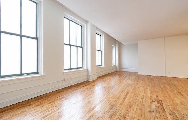 an empty living room with hardwood floors and large windows at 26 West, Managed by Buckingham Urban Living, Indianapolis