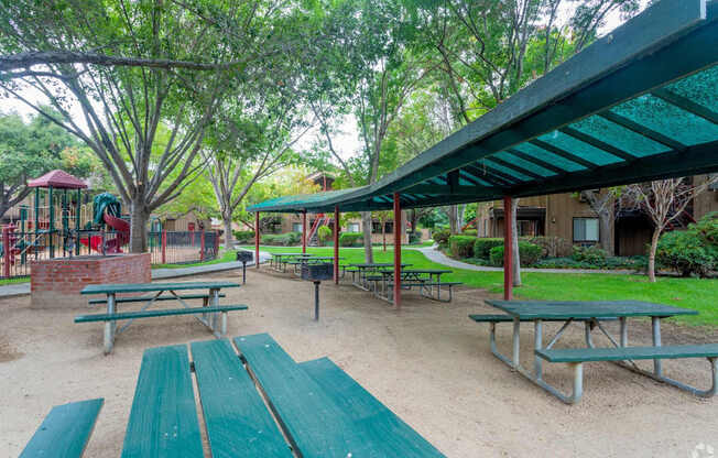 BBQ Area and playground with green benches and a red structure.