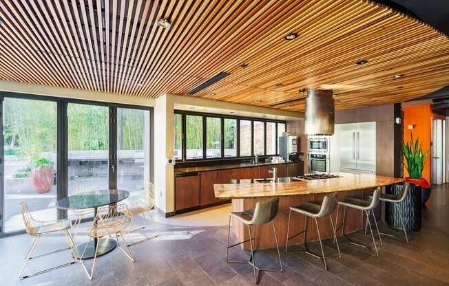 A modern kitchen with a wooden ceiling and a glass table with chairs.