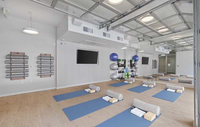 a spacious yoga room with yoga mats and a tv